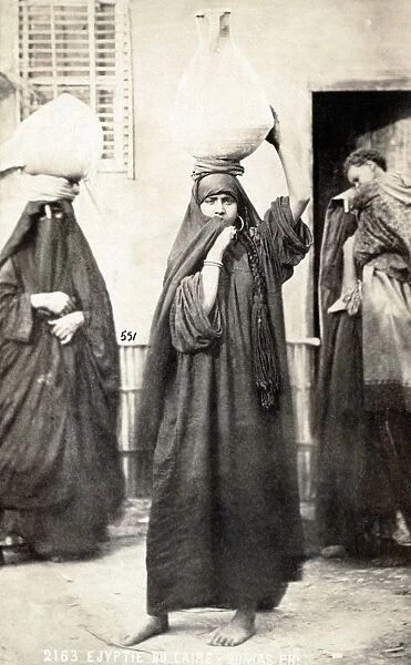 CAIRO: WOMEN. Two women carrying urns on their heads and another woman with a child on her back