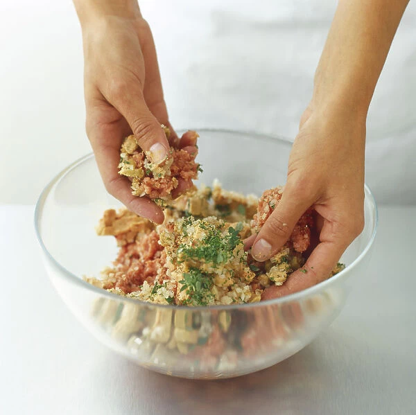 Using hands to mix diced foie gras, minced veal, shallots and herbs in a glass bowl