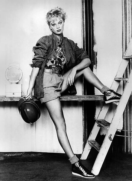 Shorts and Shapely. Model rests her foot on a ladder, holding a hard hat