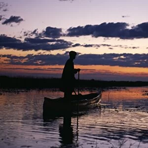 Zambia Game scout poling mokorro along Lukulu River at sunset