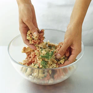 Using hands to mix diced foie gras, minced veal, shallots and herbs in a glass bowl