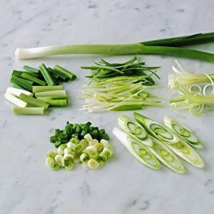 Whole, chopped and sliced spring onion on marble worktop