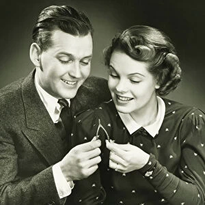Couple pulling wishbone in studio, (B&W), close-up, portrait