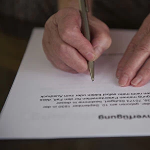 Hands of a 82-year-old woman signing a living will, Germany