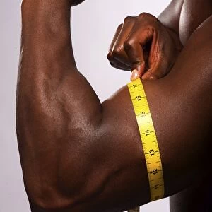 Man measuring his biceps with a tape measure