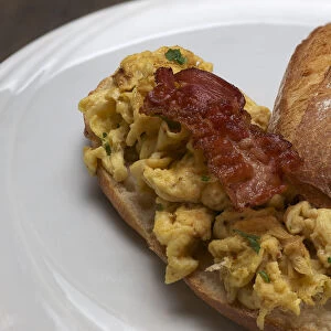 Scrambled eggs with fried bacon on a rustic roll