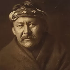 A Navajo man, head-and-shoulders portrait, wearing blanket and headband, facing front, c1904. Creator: Edward Sheriff Curtis